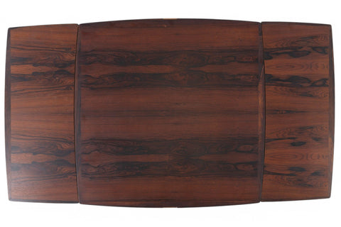 Top-down view of a rosewood dining table, draw-leaf ends ready to extend