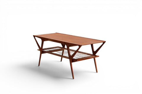 Side view of Danish teak coffee table with cane magazine shelf — 1950s Scandinavian modern