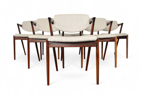 Set of six wooden dining chairs with beige cushions on a white background