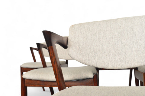 Set of wooden chairs with beige cushions on a white background