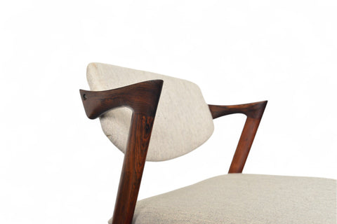 Chair with wooden armrests and beige cushion on a white background