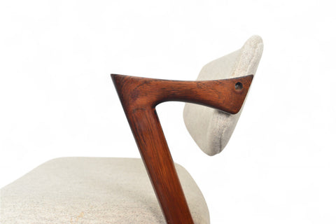 Close-up of a wooden chair armrest with a white cushion on a white background