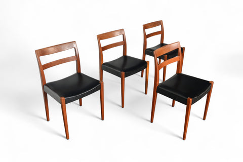 Four wooden chairs with black seats on a white background