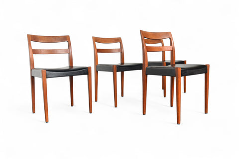 Four wooden chairs with black seats on a white background