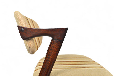 Close-up of a wooden chair with a beige cushion on a white background