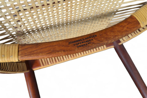 A pair of Hans Wegner JH-501 round chairs with teak wood frames and cane seating, displayed against a white background. - Close-up View