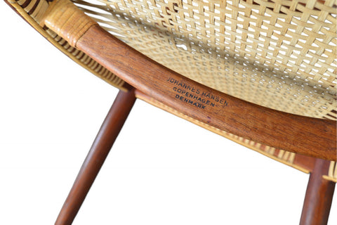 A pair of Hans Wegner JH-501 round chairs with teak wood frames and cane seating, displayed against a white background. - Close-up View