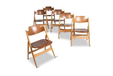 Row of Scandinavian modern dining chairs with sloped backs and round legs