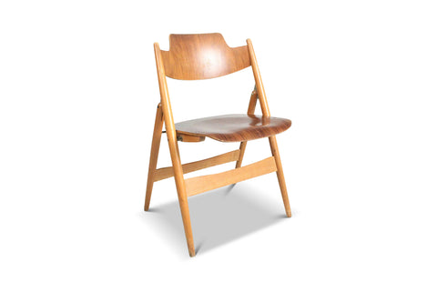 Profile view of a classic European folding chair with scooped seat